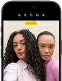 Vista frontal do iPhone 18 Pro, na cor preto, a mostrar dois modelos a posar para a câmara, para ilustrar a câmara frontal Center Stage